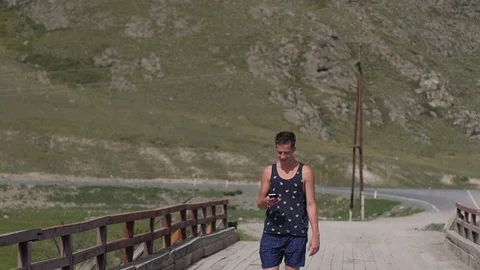 Young handsome man walking in the mountains. A man talking on the phone against Stock Footage 105567925