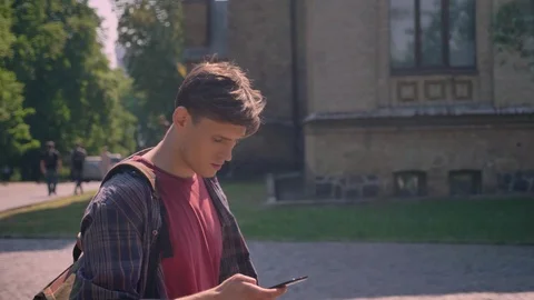 Young handsome man is walking through street in daytime in summer, tapping on Video stock 91725097