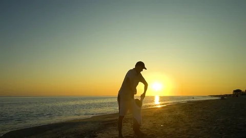 A young handsome man walks with his little daughter along the seashore at sunset Stock Footage 98933232