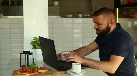 Young, handsome man working with documents and laptop in restaurant Stock Footage 67993481