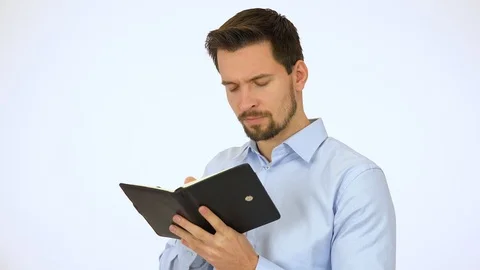 A young handsome man writes into a notebook - white screen studio Stock-Footage 115101487