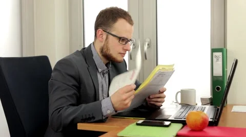 Young, handsome men sitting behind the desk and reading notes. (40) Stock Footage 49340156