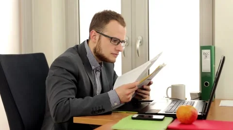 Young, handsome men sitting behind the desk and reading notes. (40) Stock Footage 49340325
