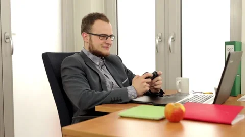 Young, handsome men sitting behind the desk and playing on his computer Stock Footage 49341316