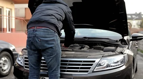 Young, handsome men standing behind his car and looking into engine. Stock Footage 49337673