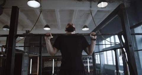 Young handsome muscular Caucasian man doing pull-ups, jumping off to rest during Video stock 116806853