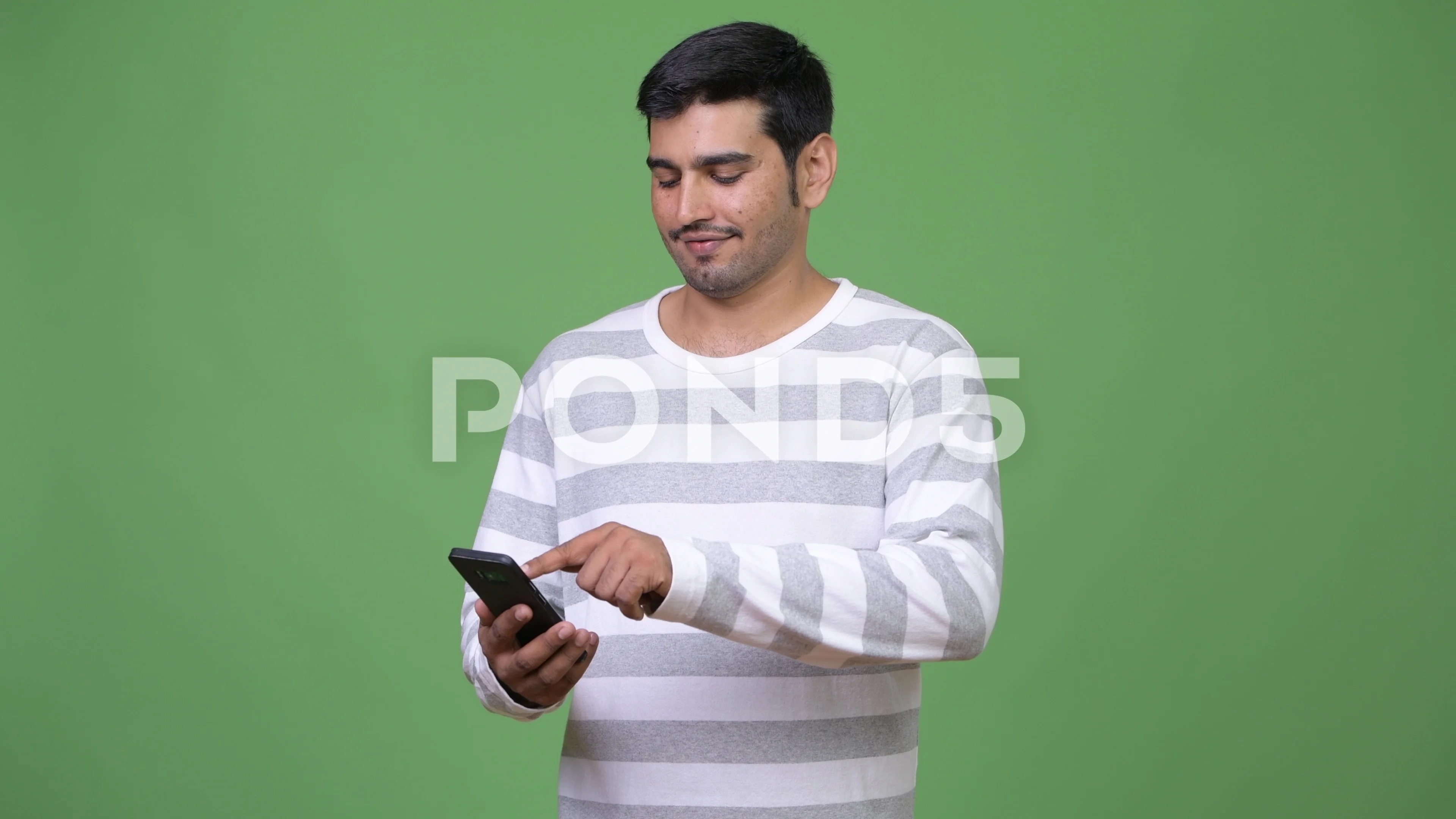 Young handsome Persian man using phone