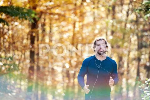 Young handsome runner outside in sunny autumn nature Stock Photos