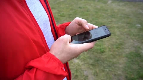 Young handsome runner in red hook wear surfes internet on cellphone Stock Footage 90845924