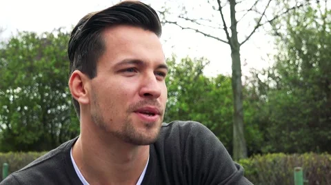 Young handsome satisfied man talks about something in park Stock-Footage 64683053