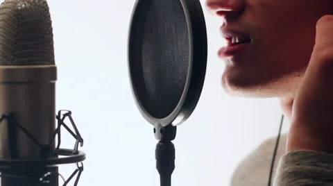 Young, handsome singer singing into a microphone headphones holding hands. Stock-Footage 58628276