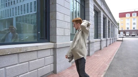 Young handsome stylish man is looking at herself in the window and wearing the Stock Footage 78926894