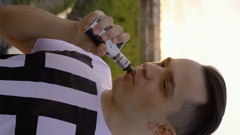 A young handsome white bearded man with smartphone is vaping an electronic cigar Stock Footage 114127809