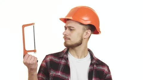 Young handyman thoughtfully selecting between two saws for his next project Stock Footage 311982686