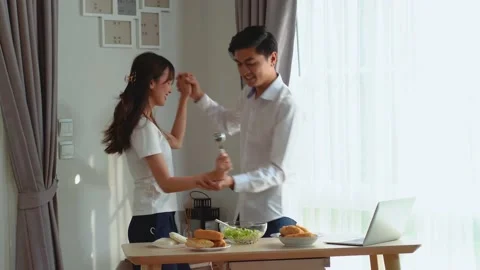 Young happy active asian couple dancing laughing together preparing food at home Stock Footage 154394007