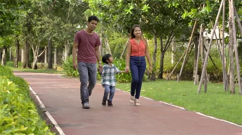 Young happy Asian family walking in the park together Stock Footage