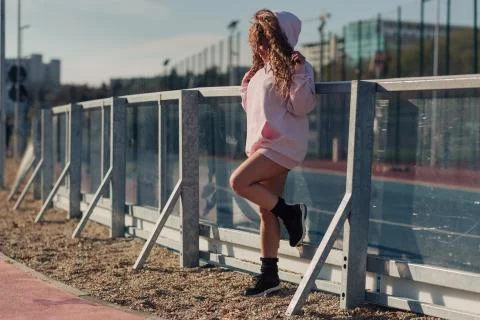 Young happy attractive woman posing on a fence near a running track Stock Photos