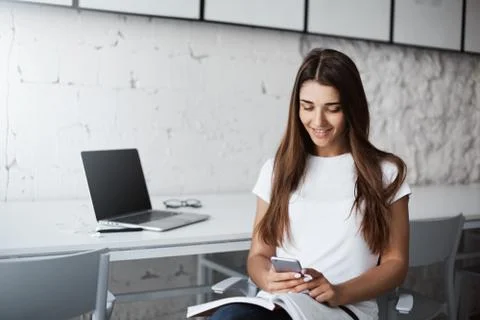 Young happy beautiful lady using a smart phone to learn new language in a bright Stock Photos
