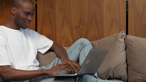 Young happy black man communicates online on a laptop. Random guy sitting on the Stock Footage 168742323