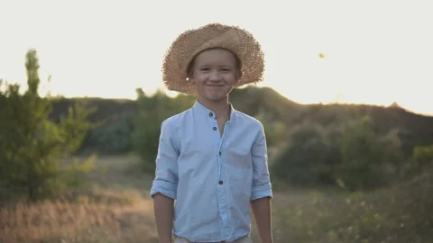 Young happy boy in the hat smiling on camera in the middle of the field Stock Footage 115986534