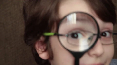 Young, happy boy looking through a magnifying glass while wearing eyeglasses Stock Footage 60808050