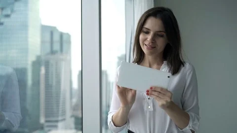 Young, happy businesswoman using tablet computer standing by window at home Stock Footage