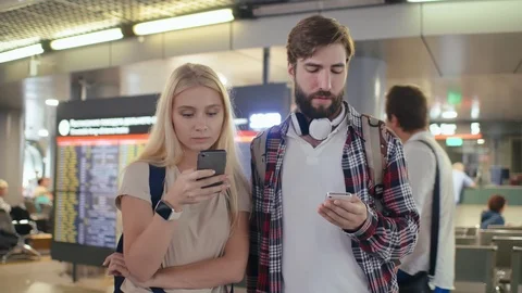 Young happy caucasian couple checking the flight schedule using smartphones Stock Footage