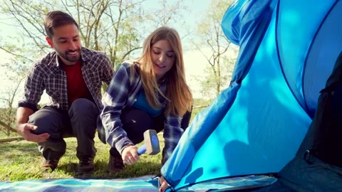 Young happy couple assembling tent together outdoors Stock Footage 333386760
