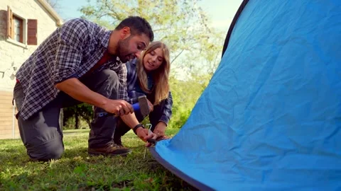 Young happy couple assembling tent together outdoors Video stock 333386902