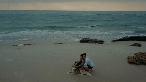 Young happy couple having fun with husky dog on beach Stock Footage 117361243