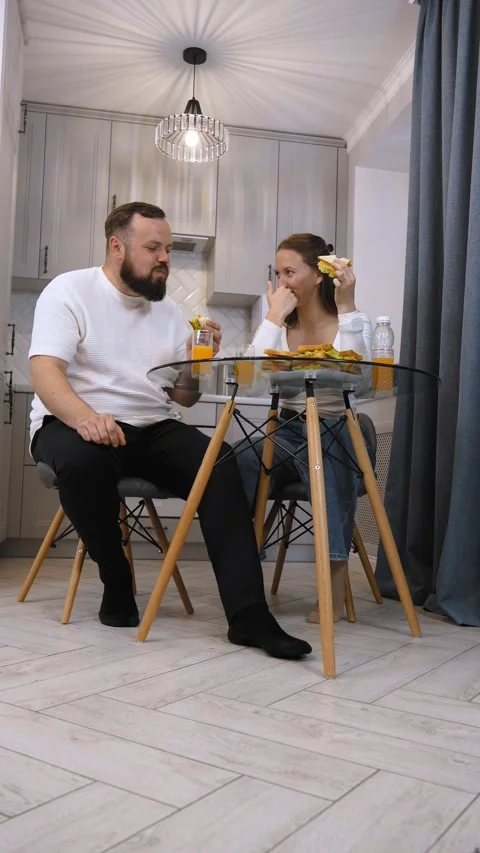 Young happy couple having fun eating sandwiches for breakfast in the kitchen. Stock Footage 320498958
