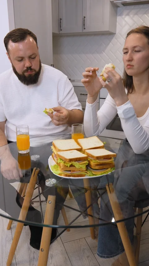 Young happy couple having fun eating sandwiches for breakfast in the kitchen. Stock Footage 320499001