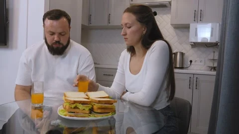 Young happy couple having fun eating sandwiches for breakfast in the kitchen. Stock Footage 320499073