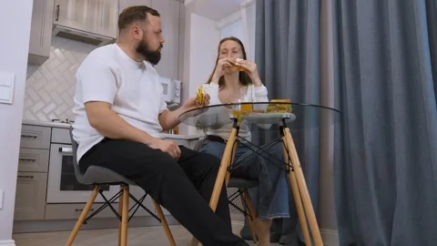 Young happy couple having fun eating sandwiches for breakfast in the kitchen. Stock Footage 320499718