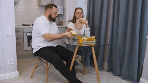 Young happy couple having fun eating sandwiches for breakfast in the kitchen. Stock Footage 320640589