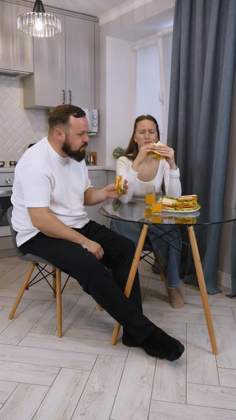 Young happy couple having fun eating sandwiches for breakfast in the kitchen. Stock Footage 320640935