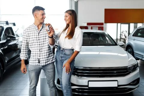 Young happy couple just bought a new car in a dealership Stock Photos