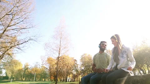 Young happy couple listening to music on headphones at the park Stock Footage 59554754