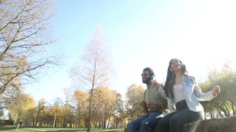 Young happy couple listening to music on headphones at the park Stock Footage 59554755