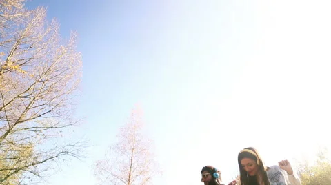 Young happy couple listening to music on headphones at the park Stock Footage 59554761
