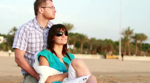 Young happy couple looking at something on the beach Stockbeeldmateriaal 10763891