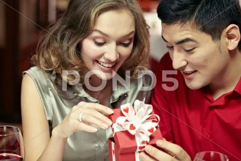Young happy couple looking together at a small gift box Stock Photos