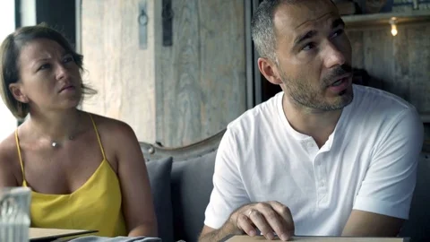 Young, happy couple placing order to waiter in cafe, 4K Видео 70574077