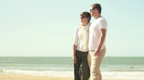 Young happy couple pointing at something on the beach Stockbeeldmateriaal 10851384