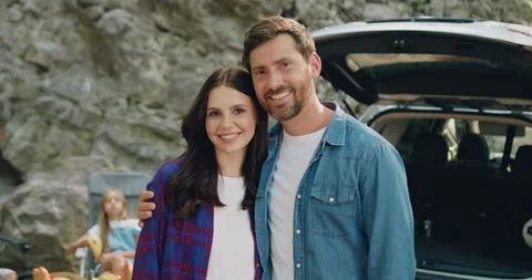Young happy couple posing looking at camera standing near car with happy Stock Footage 251653926