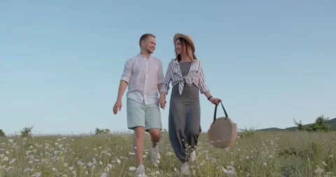Young happy couple running in field of blooming daisies holding hands Stock Footage 135883009