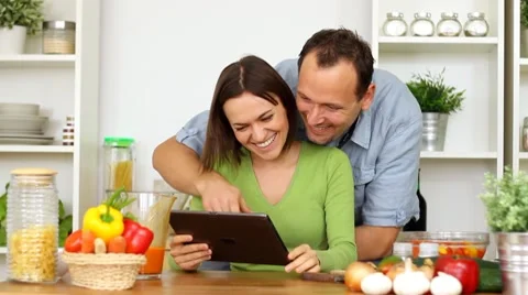 Young happy couple with tablet computer by the table in kitchen HD Stock Footage 8988292