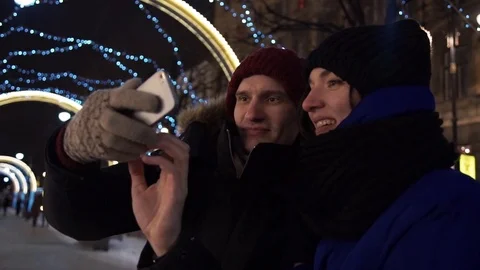 Young happy couple taking selfie using smartphone talking on a busy city street Stock Footage 83926519