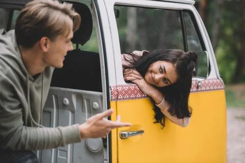 Young happy couple talking while sitting in retro styled minivan Stock Photos