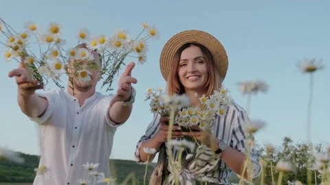 Young happy couple throwing daisies growing in the camera. Slow motion video Stock Footage 135881259